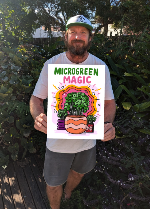 Man holding 'Microgreen Magic' plant poster outdoors.